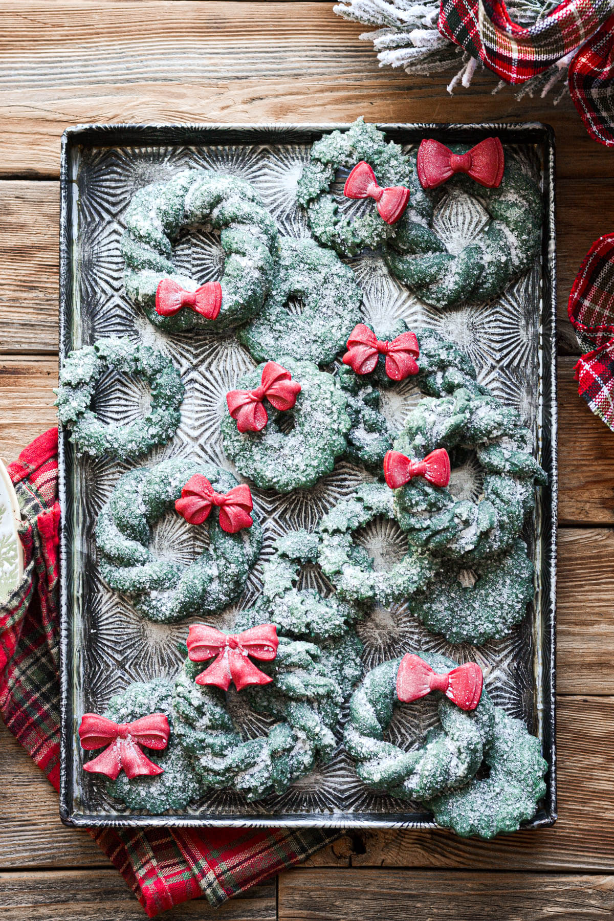 Christmas wreath cookies with red chocolate bows on a vintage baking sheet.