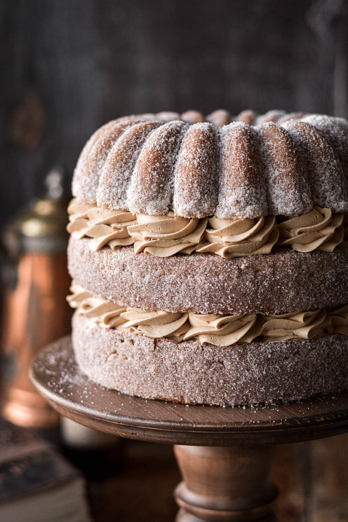 Coffee layer cake coated in espresso sugar and filled with swirls of coffee buttercream on a wooden cake stand.