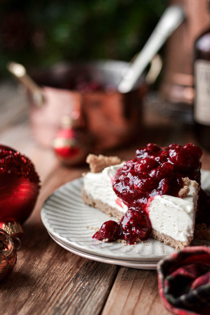 A slice of cream cheese pie topped with cranberry raspberry sauce.
