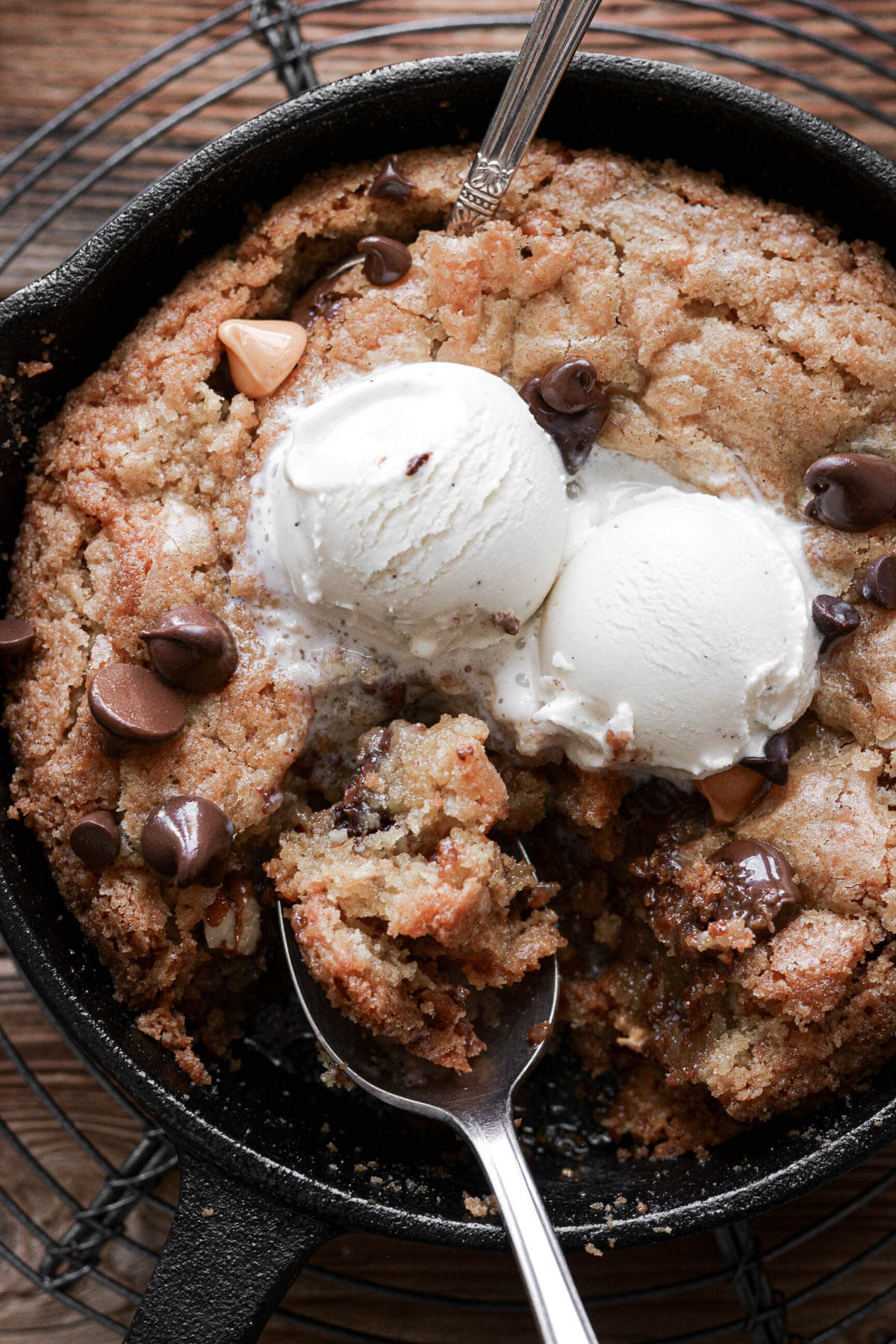 Butterscotch blondies in a skillet with ice cream and two spoons.