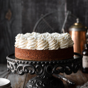 Carrot cake cheesecake on a black cake stand.