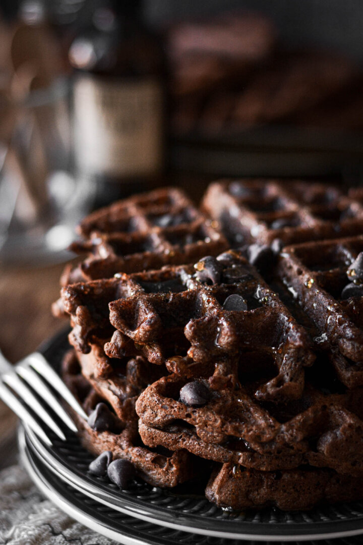 Stack of chocolate waffles topped with chocolate chips.