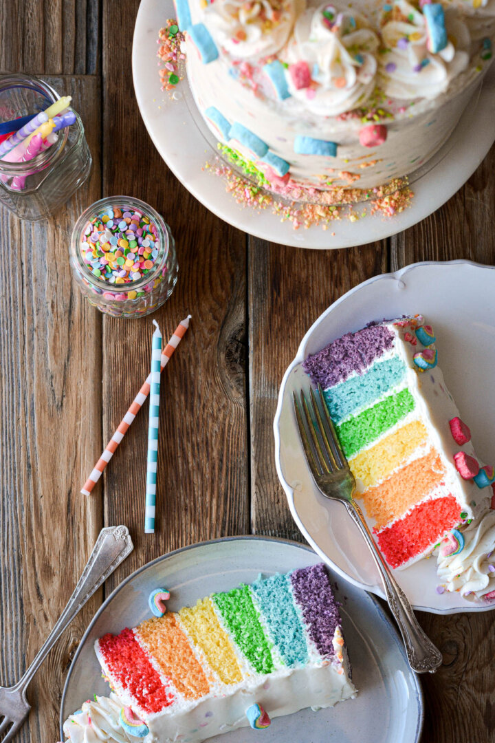 Slices of rainbow cake on plates.
