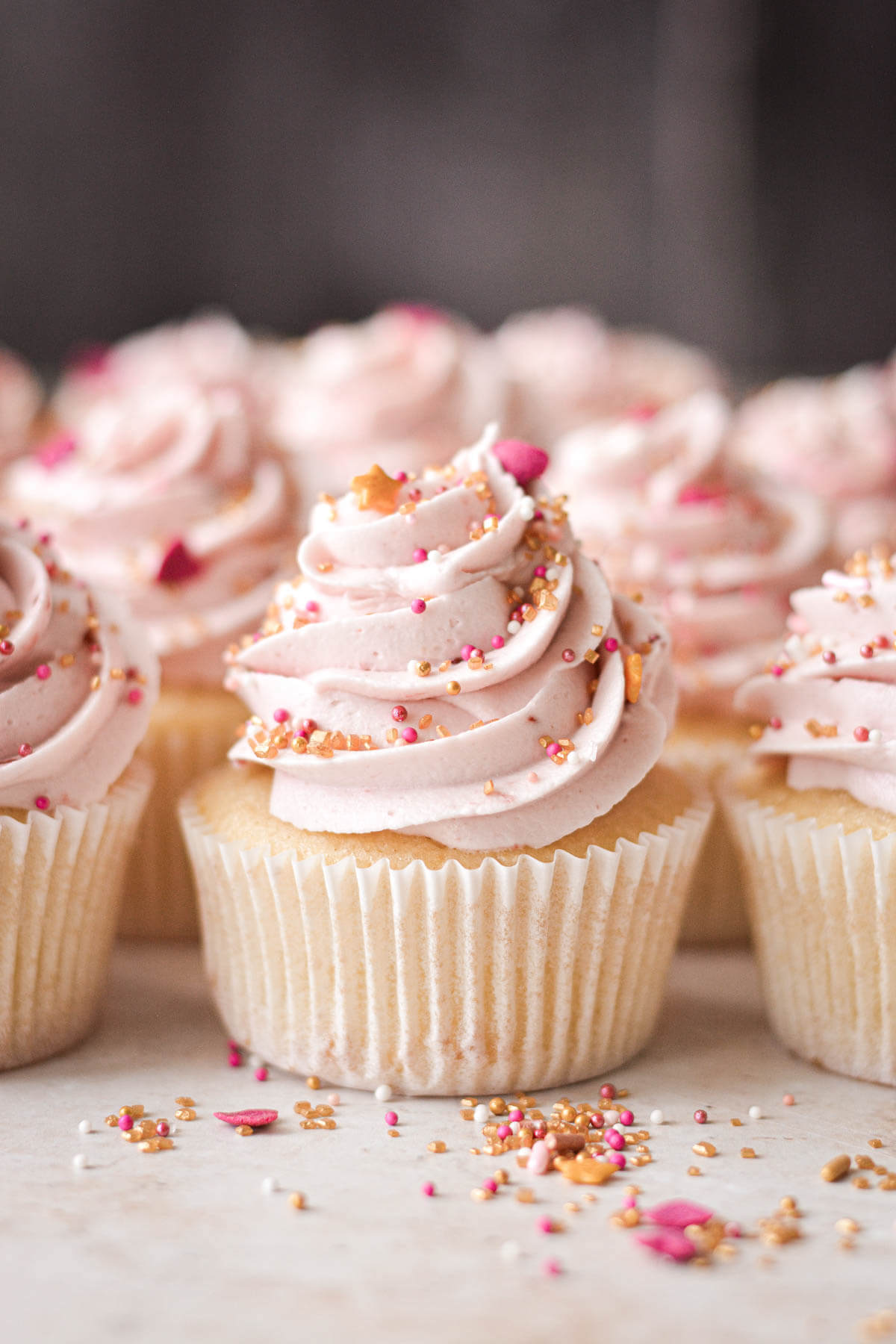 Vanilla cupcakes with raspberry buttercream and sprinkles.