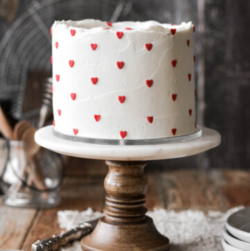 Valentine's Day cake with white buttercream and red heart sprinkles.