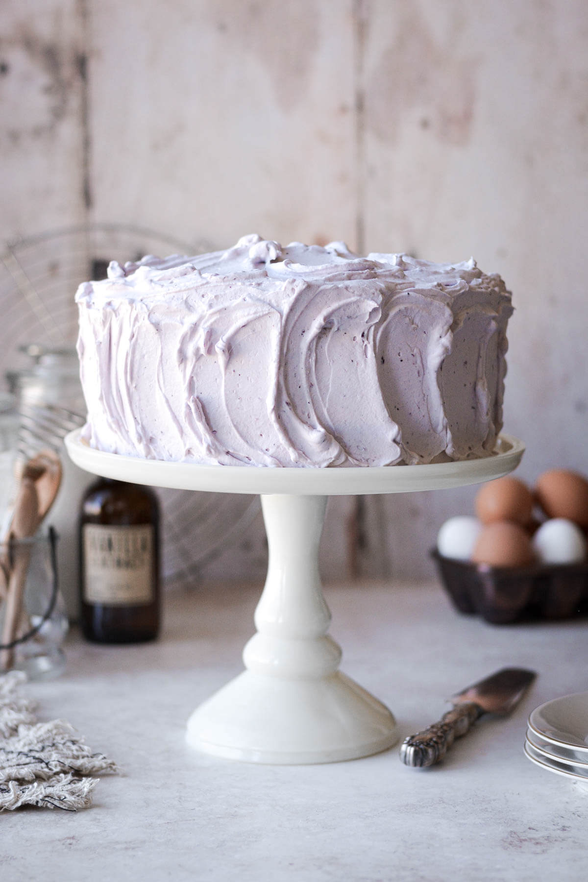 Chiffon cake on a white cake stand with blueberry whipped cream.