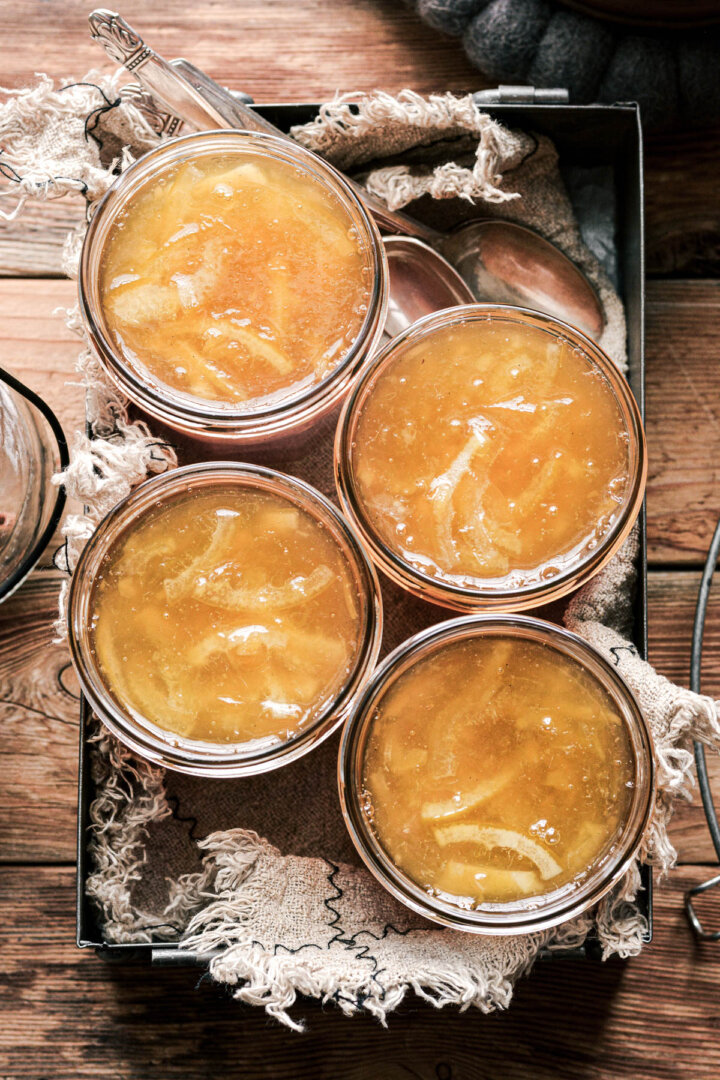 Jars of lemon marmalade in a metal tray with a linen.