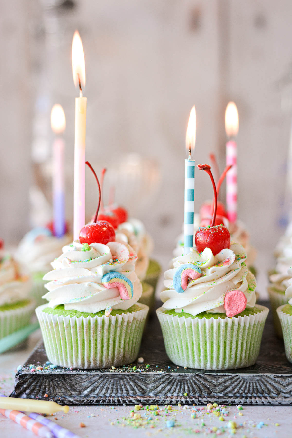 Green shamrock shake cupcakes with maraschino cherries, Lucky Charms marshmallows, and birthday candles.