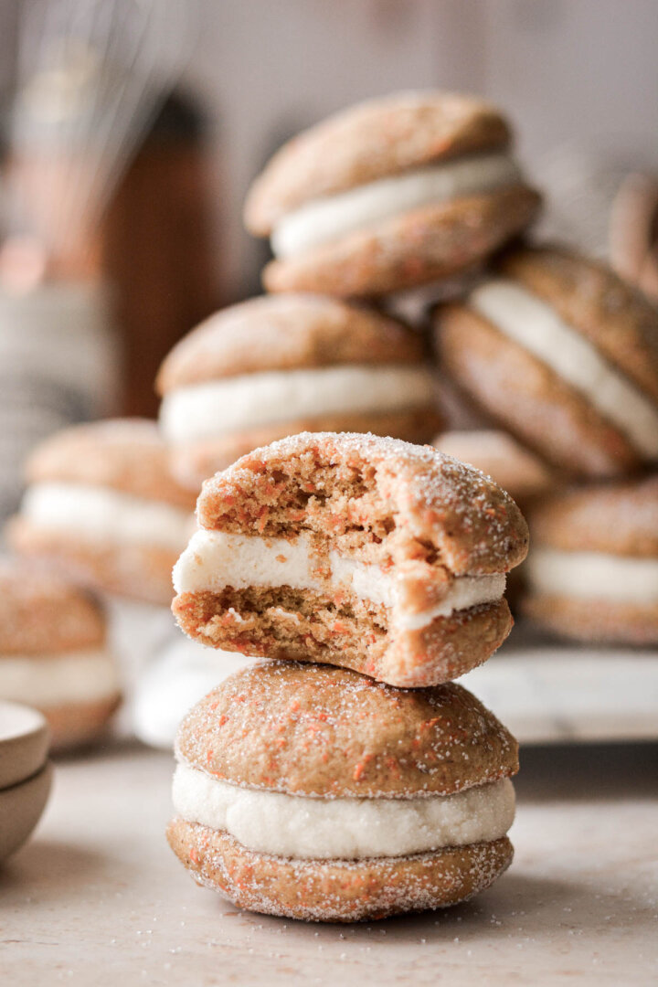 A stack of carrot cake sandwich cookies, one with a bite taken.