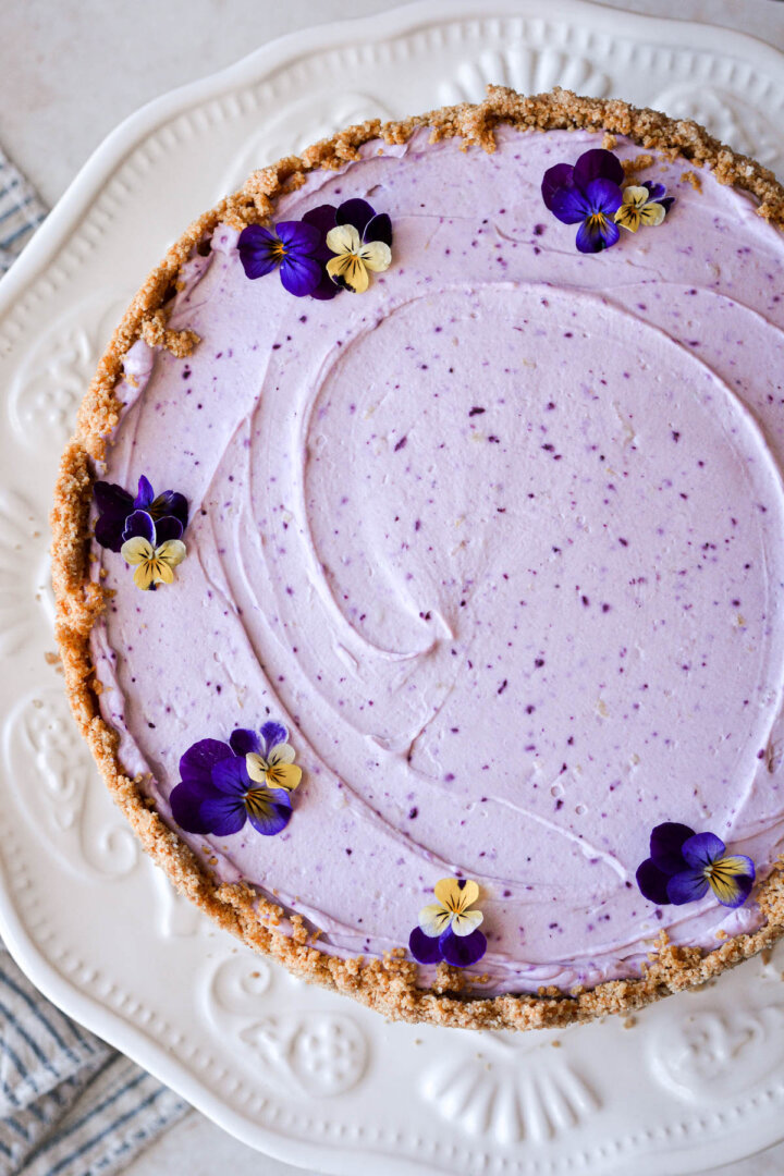 Fresh pansies arranged on top of a lemon blueberry cheesecake.