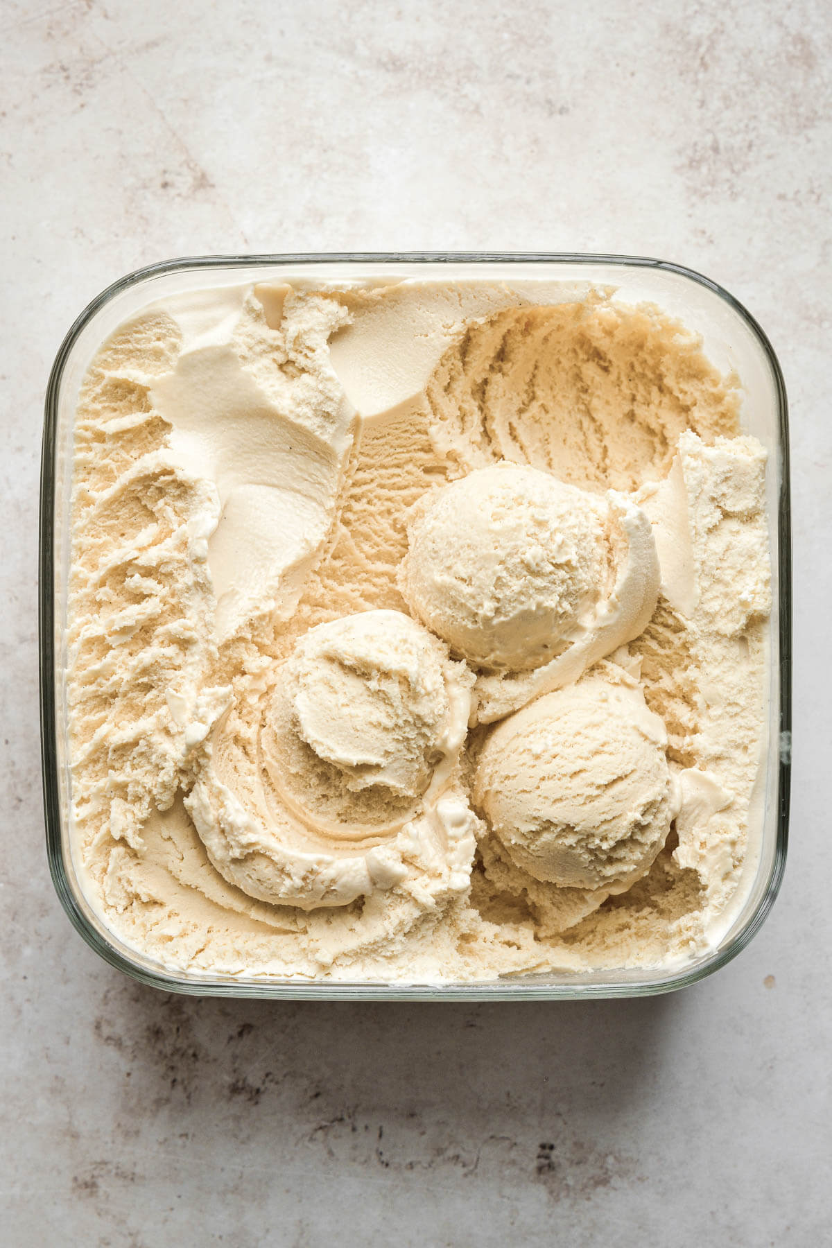 Scoops of homemade vanilla bean ice cream in a glass pan.