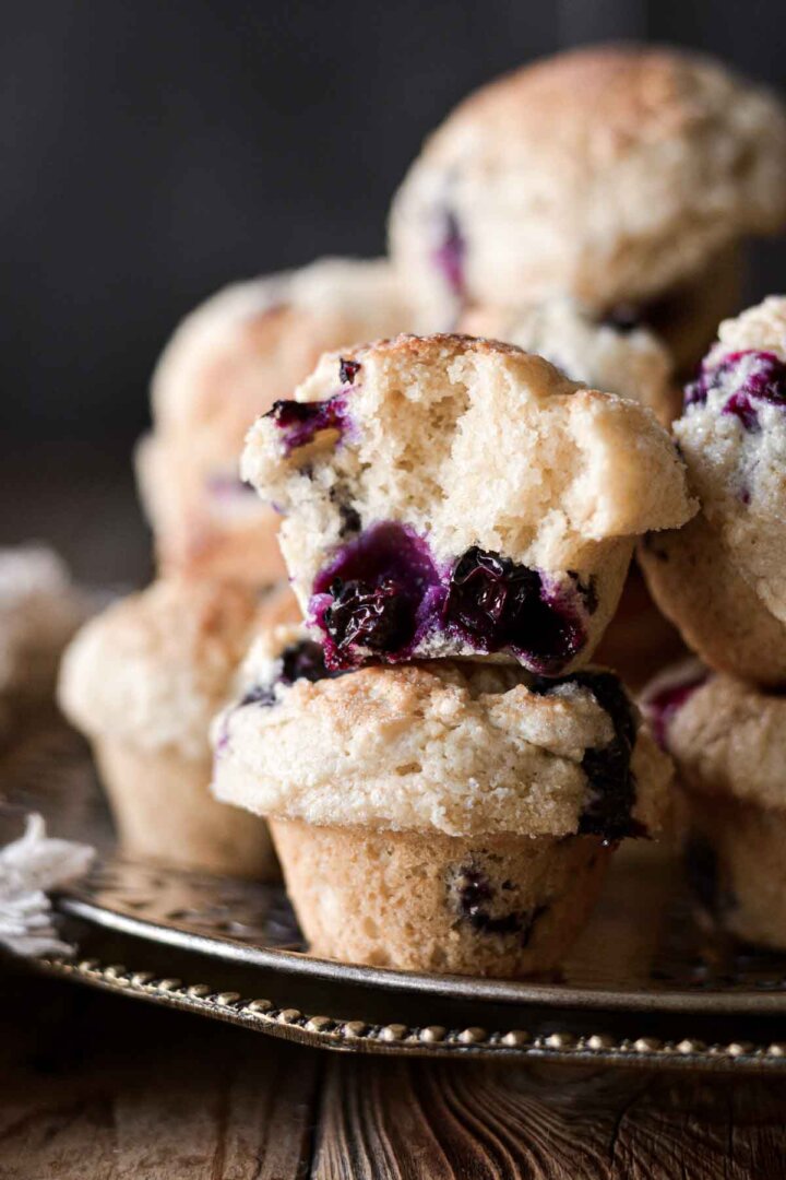 Mini blueberry muffins, one with a bite taken.