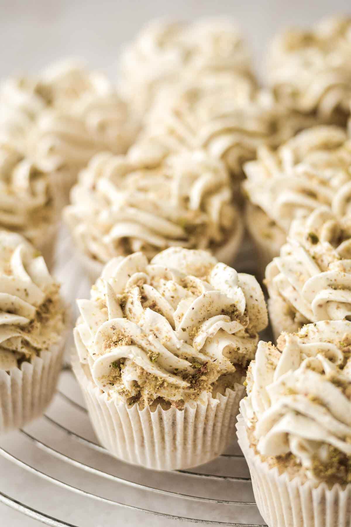 Lemon pistachio cupcakes on a cooling rack.