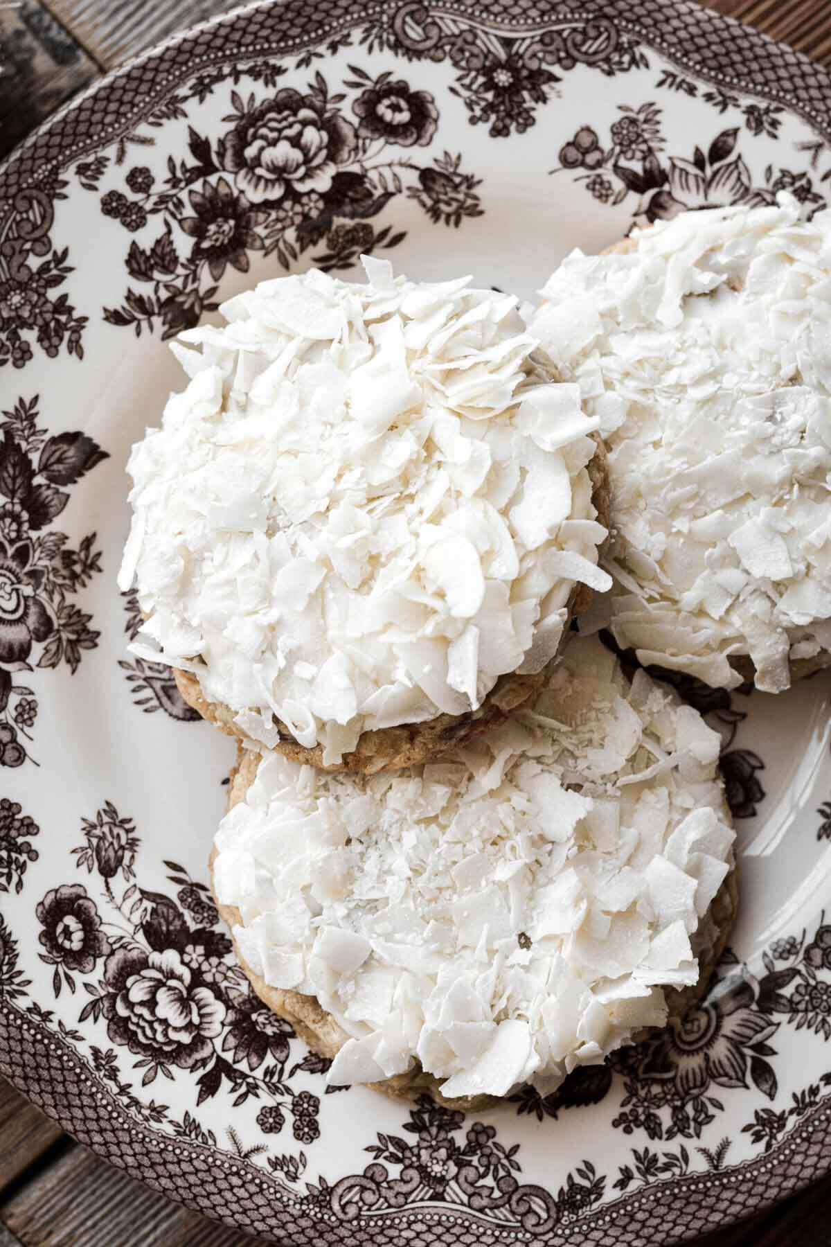 Frosted coconut cookies on a flowered plate.
