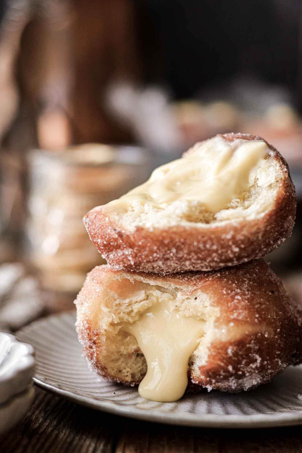 Lemon custard filled doughnuts stacked on a plate.