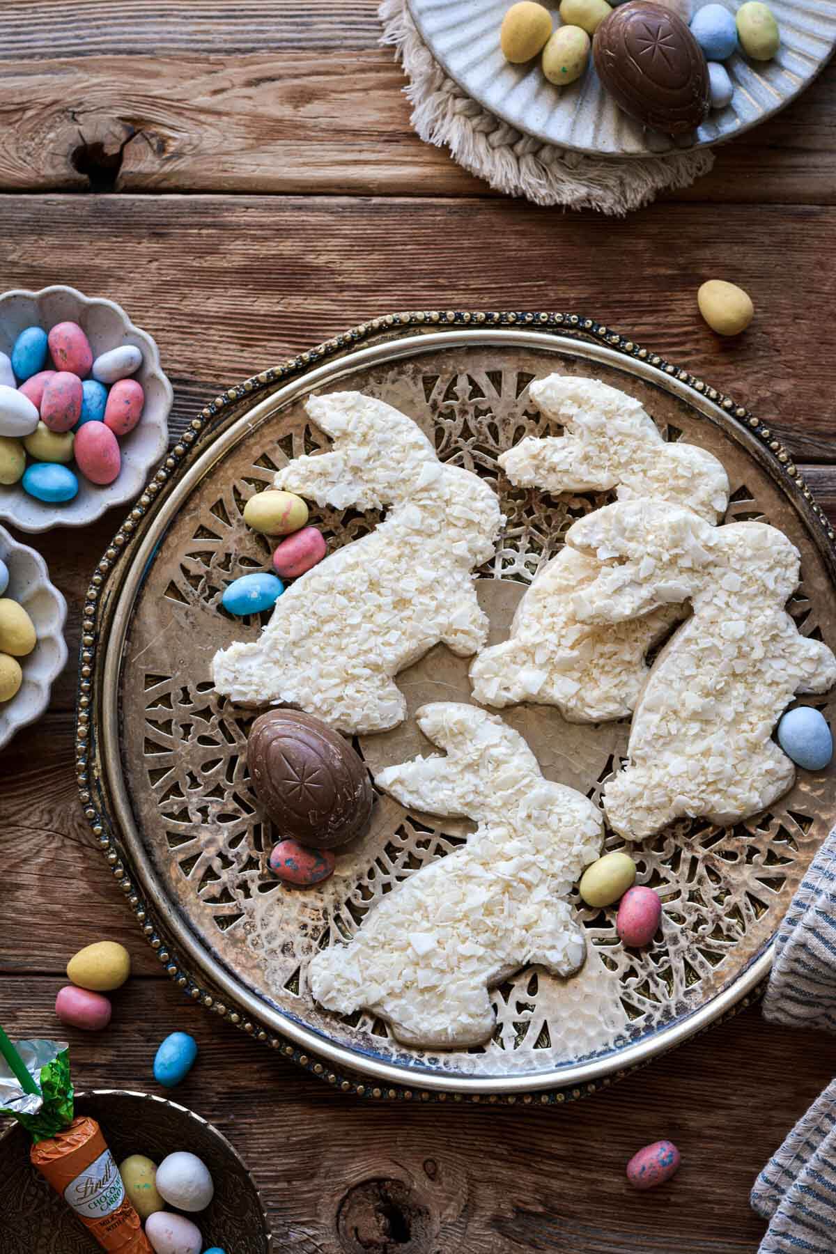 Easter bunny coconut sugar cookies on a vintage plate, surrounded by Easter candy.