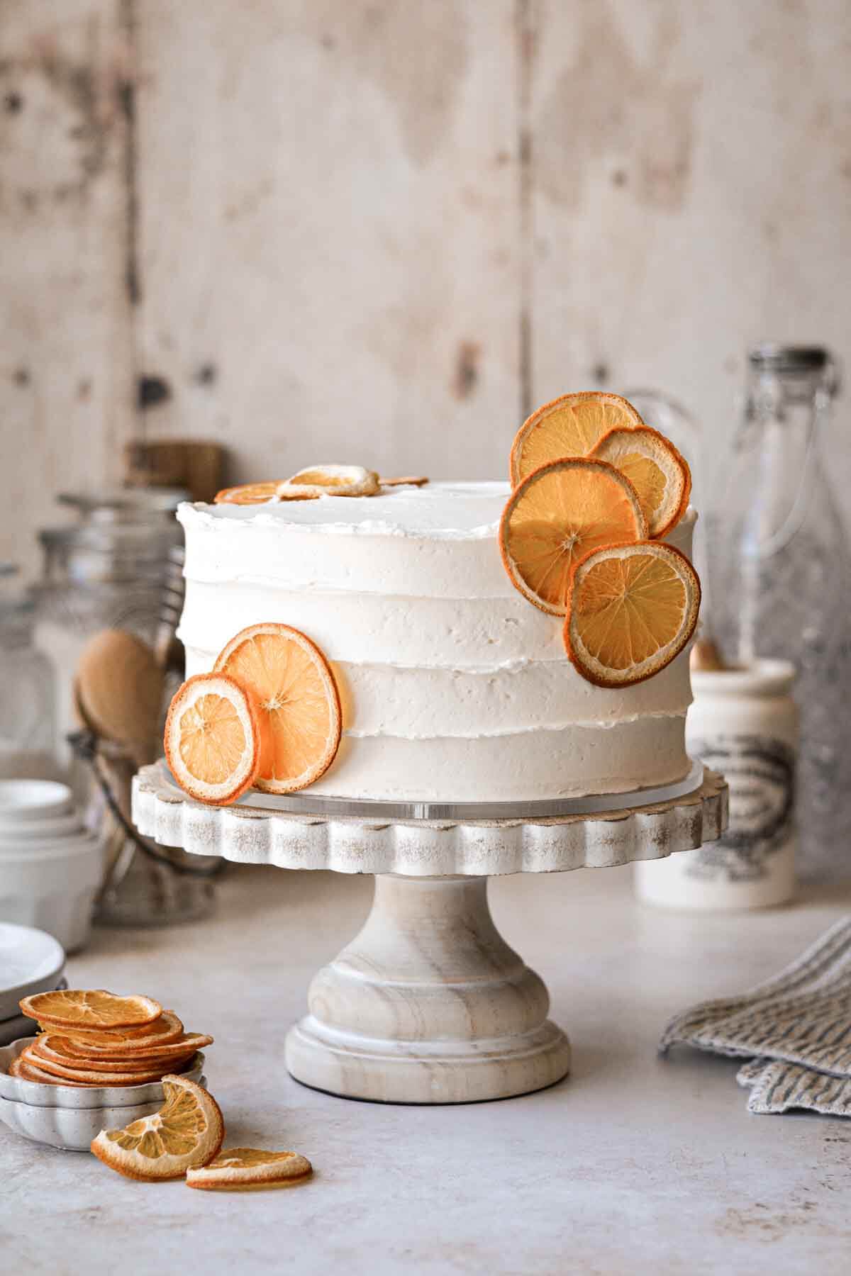 Orange cake decorated with dried orange slices on a cake stand.