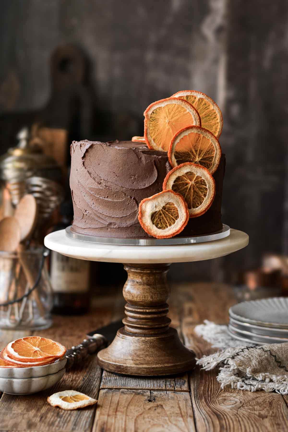 Chocolate orange cake with dried orange slices on a cake stand.