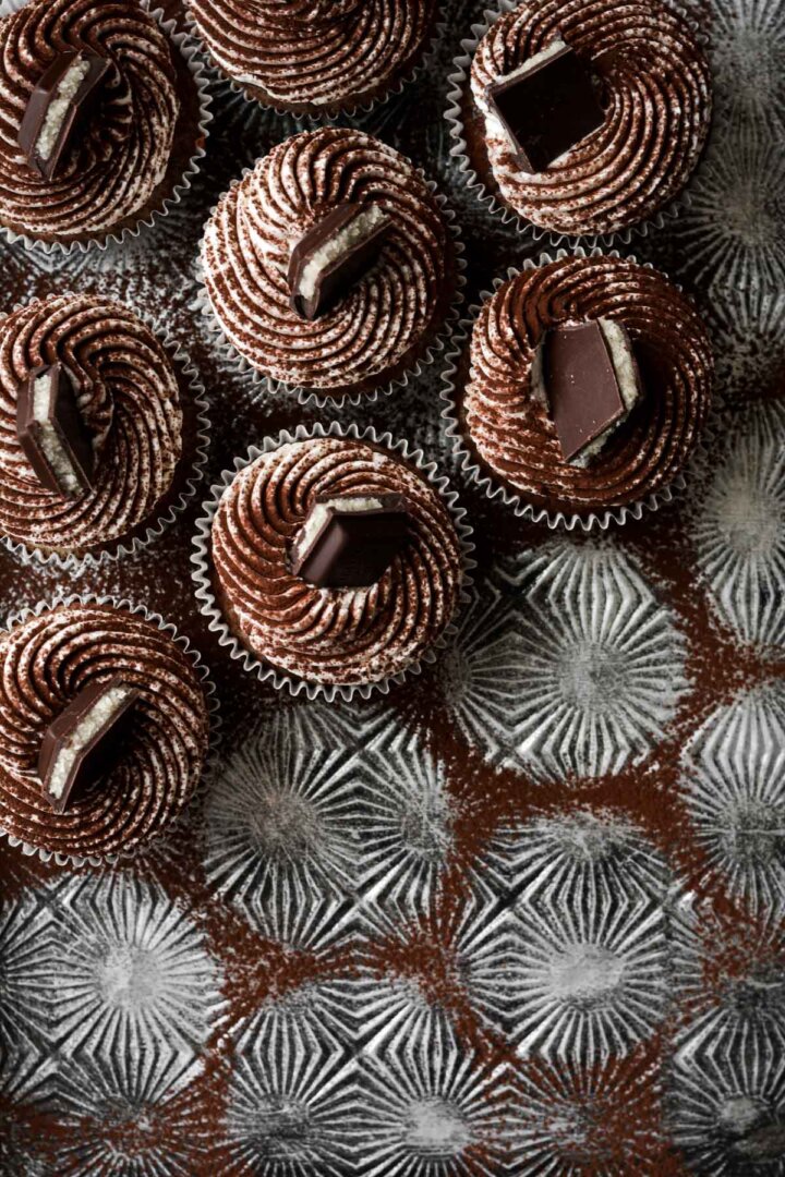 Marble cupcakes dusted with cocoa powder on a baking sheet.
