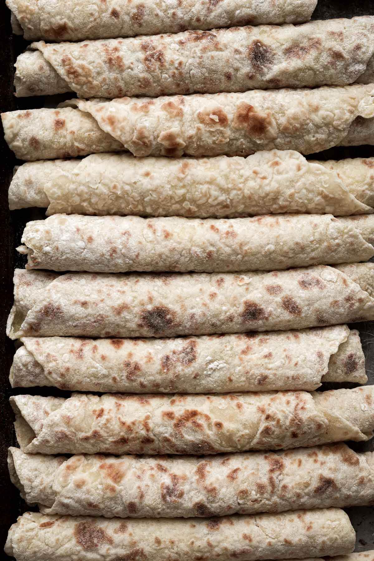 Norwegian lefse rolled up on a baking sheet.
