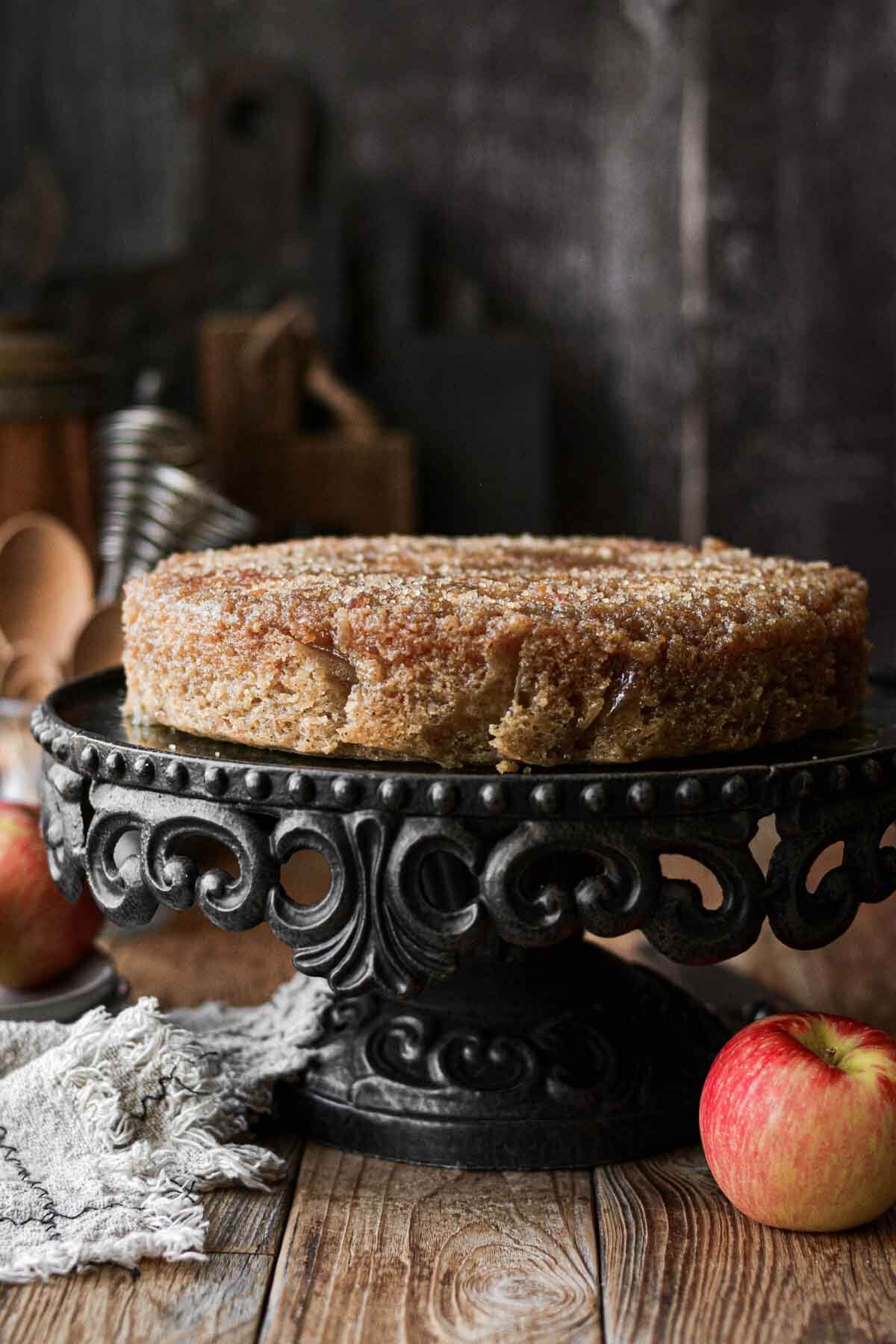Apple upside down cake on a black cake stand.