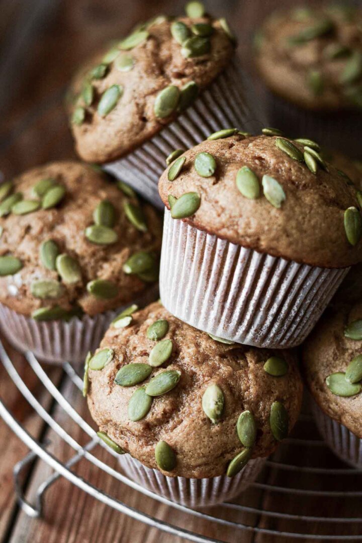 Pumpkin banana muffins with pumpkin seeds on a cooling rack.