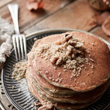Stack of walnut spice pancakes topped with chopped walnuts.