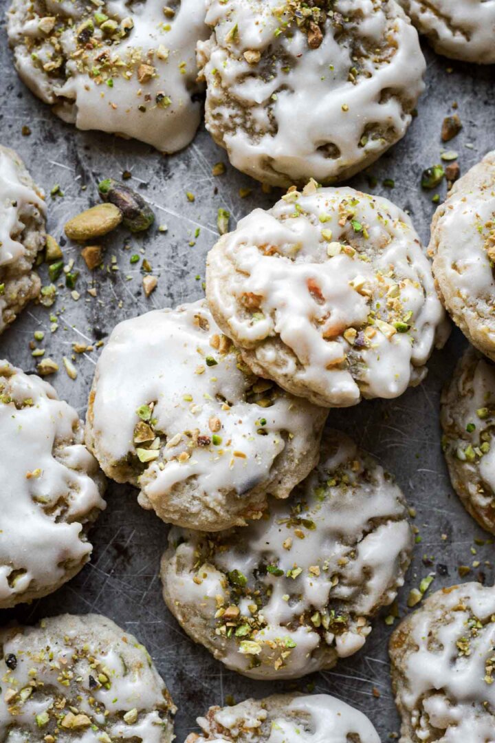 Iced apricot pistachio cookies on a baking sheet.