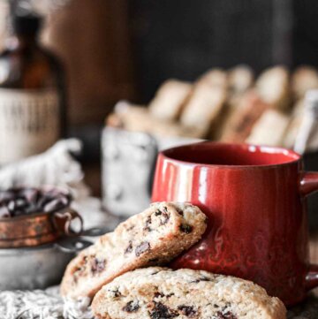 Cherry chocolate chip biscotti next to a red coffee cup.