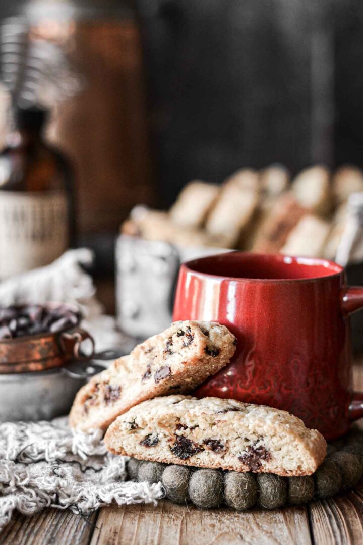 Cherry chocolate chip biscotti next to a red coffee cup.