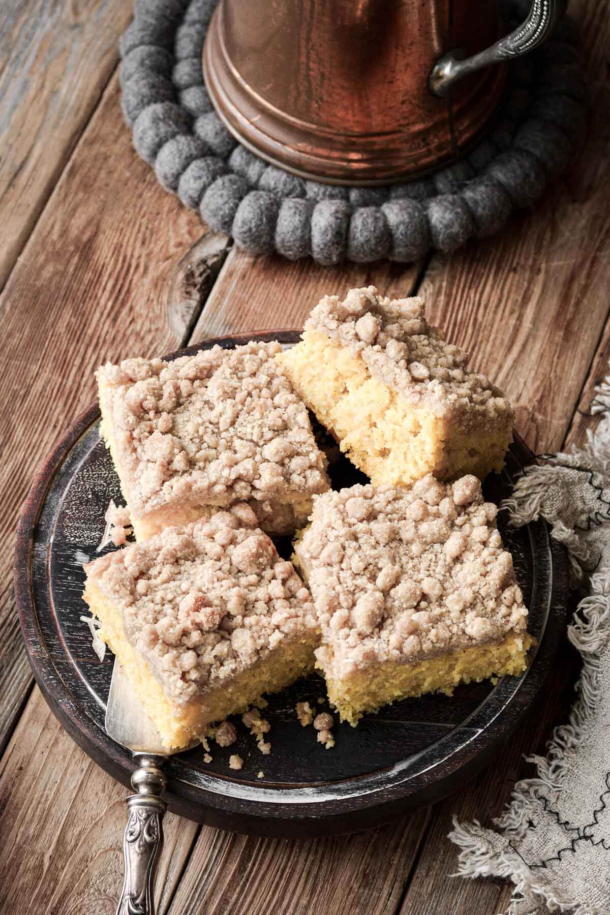 Squares of apple cornbread cake with crumb topping on a wooden plate.