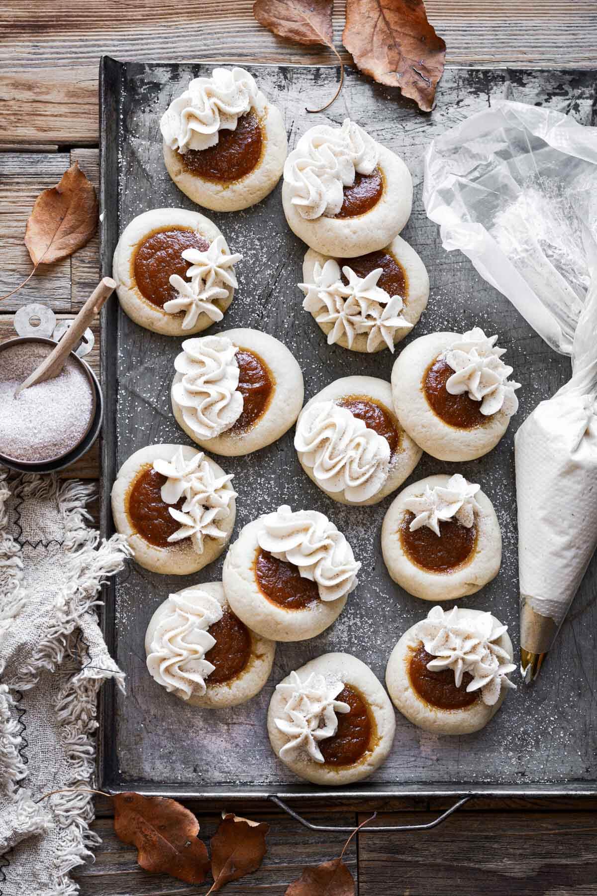 Pumpkin pie cookies with vanilla buttercream piping on a baking sheet.