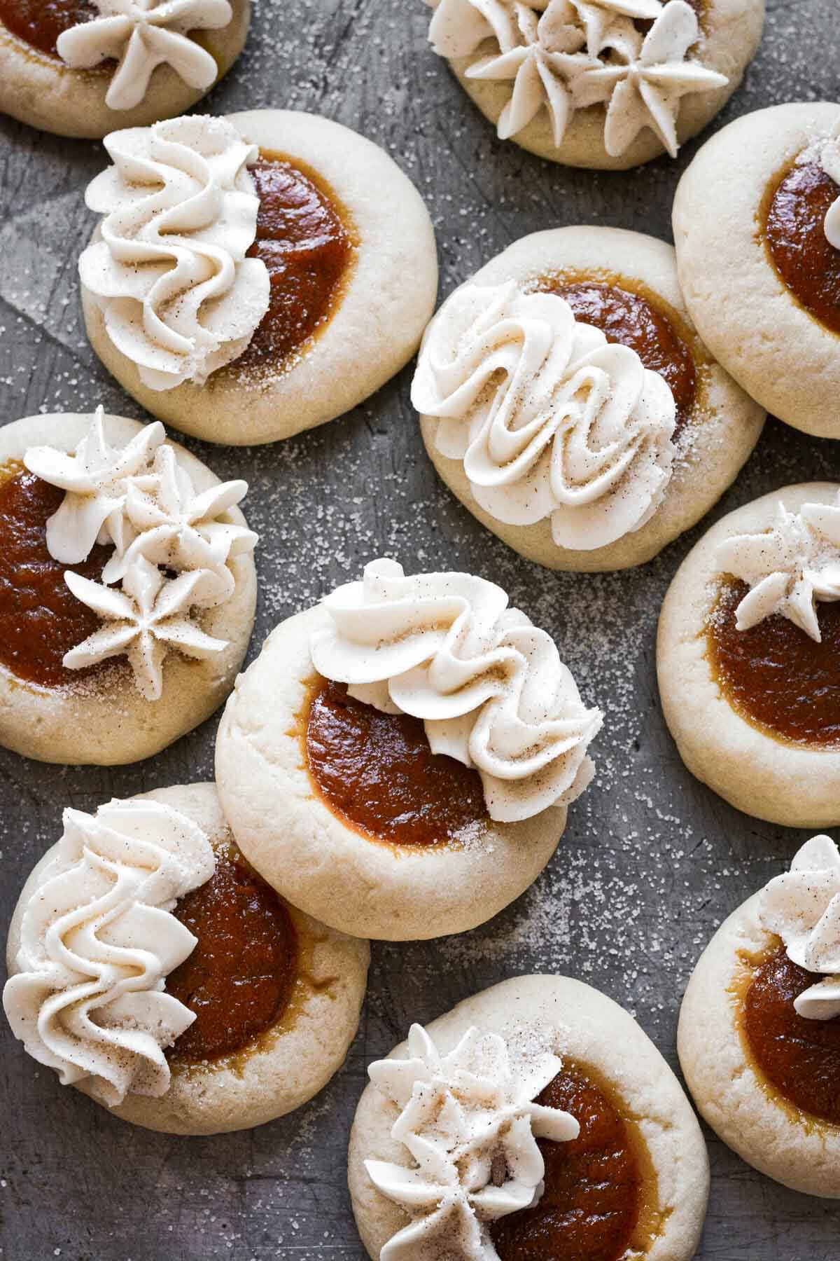 Pumpkin pie cookies with vanilla buttercream piping on a baking sheet.
