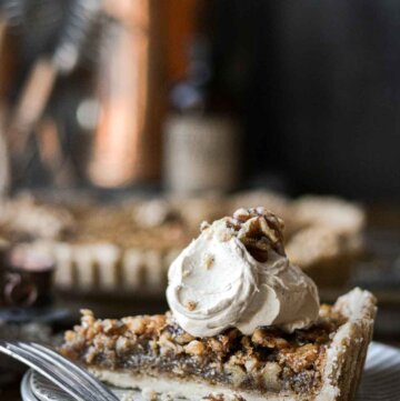Slice of walnut pie topped with coffee whipped cream.