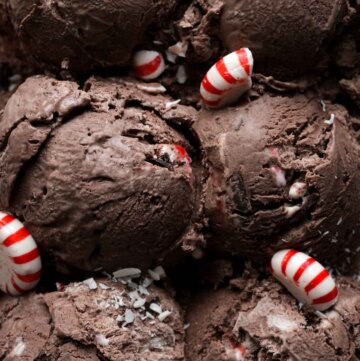 Scoops of chocolate peppermint ice cream with peppermint candy scattered around.