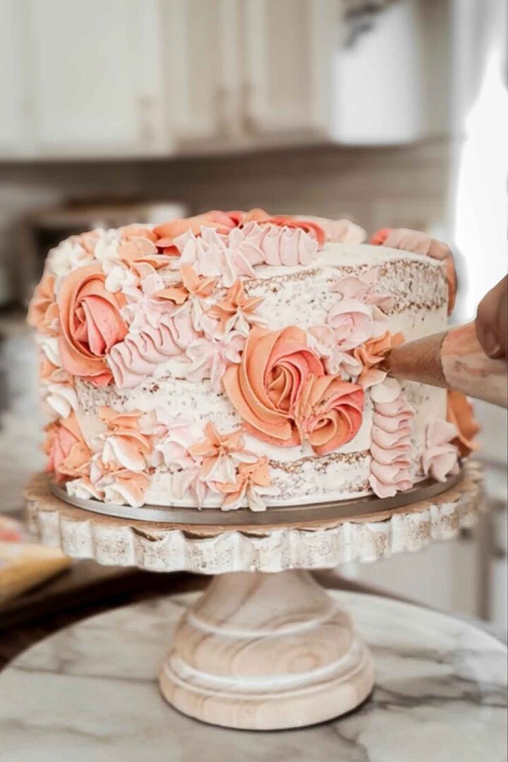 Piping orange drop flowers onto a layer cake.
