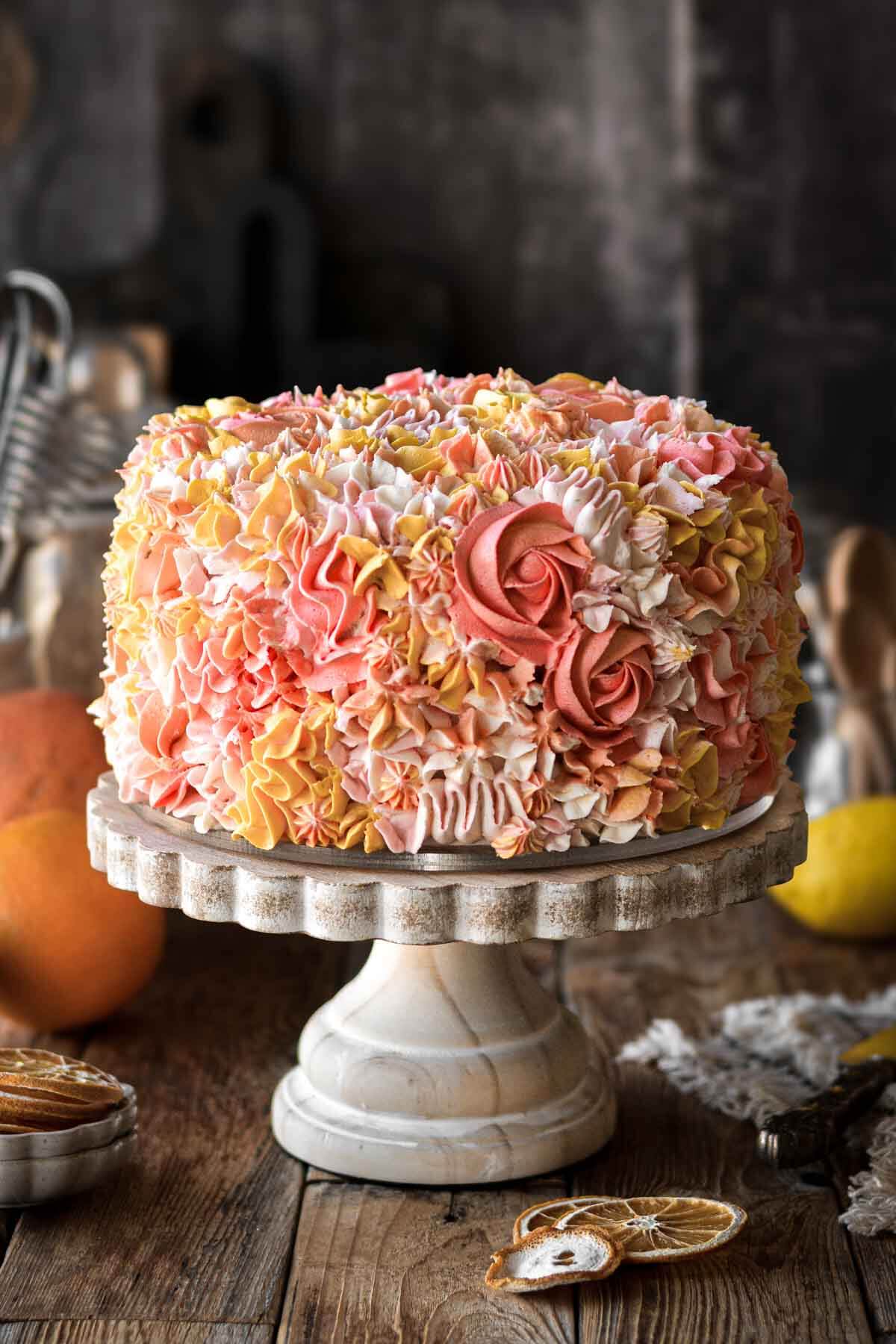 A citrus cake decorated with piped floral buttercream in shades of pink, yellow, orange and white.