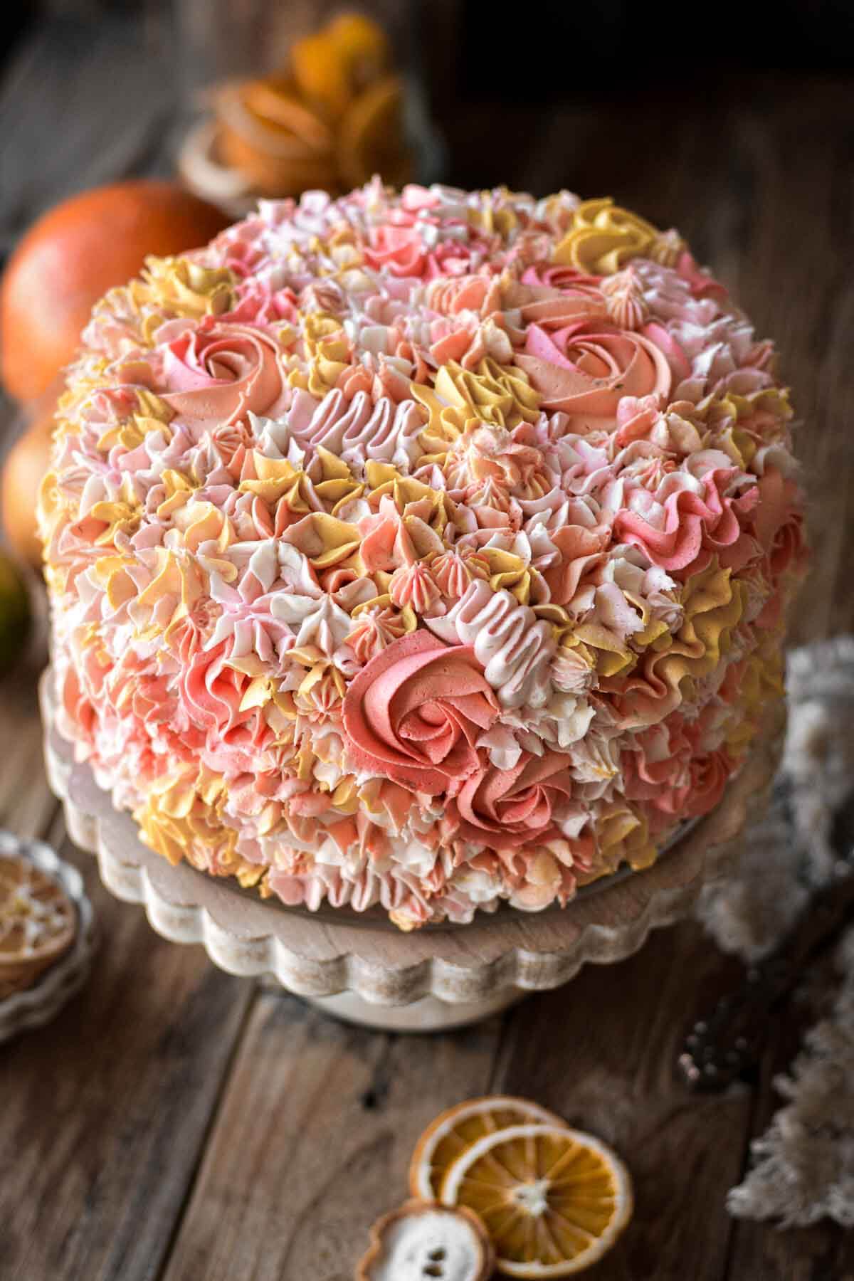 A citrus cake decorated with piped floral buttercream in shades of pink, yellow, orange and white.