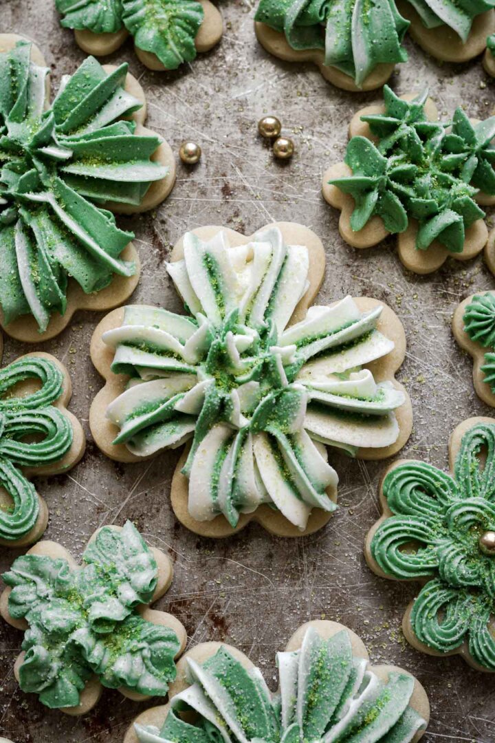Four leaf clover cutout cookies decorated with green and white buttercream for St Patrick's Day.
