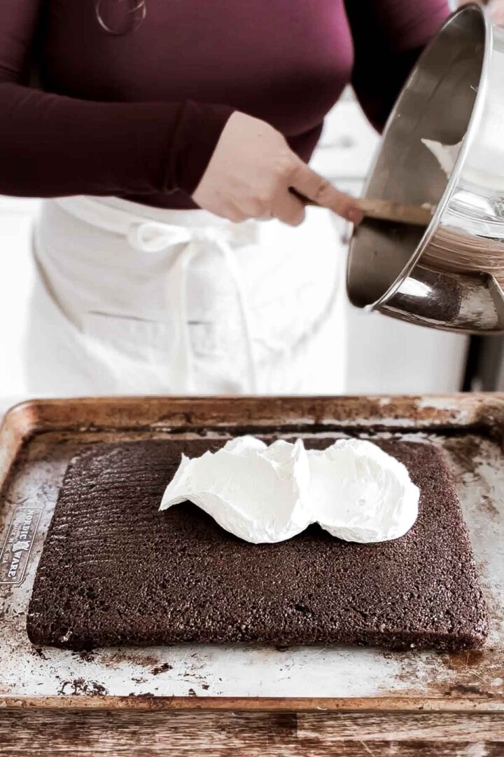 Spreading whipped vanilla buttercream onto a chocolate cake.