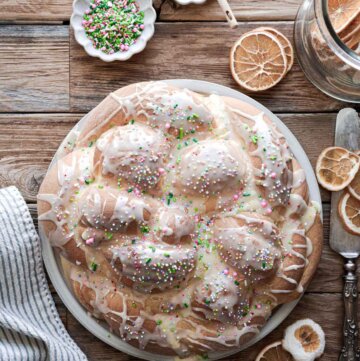 Braided loaf of orange cardamom Easter bread with icing and sprinkles.