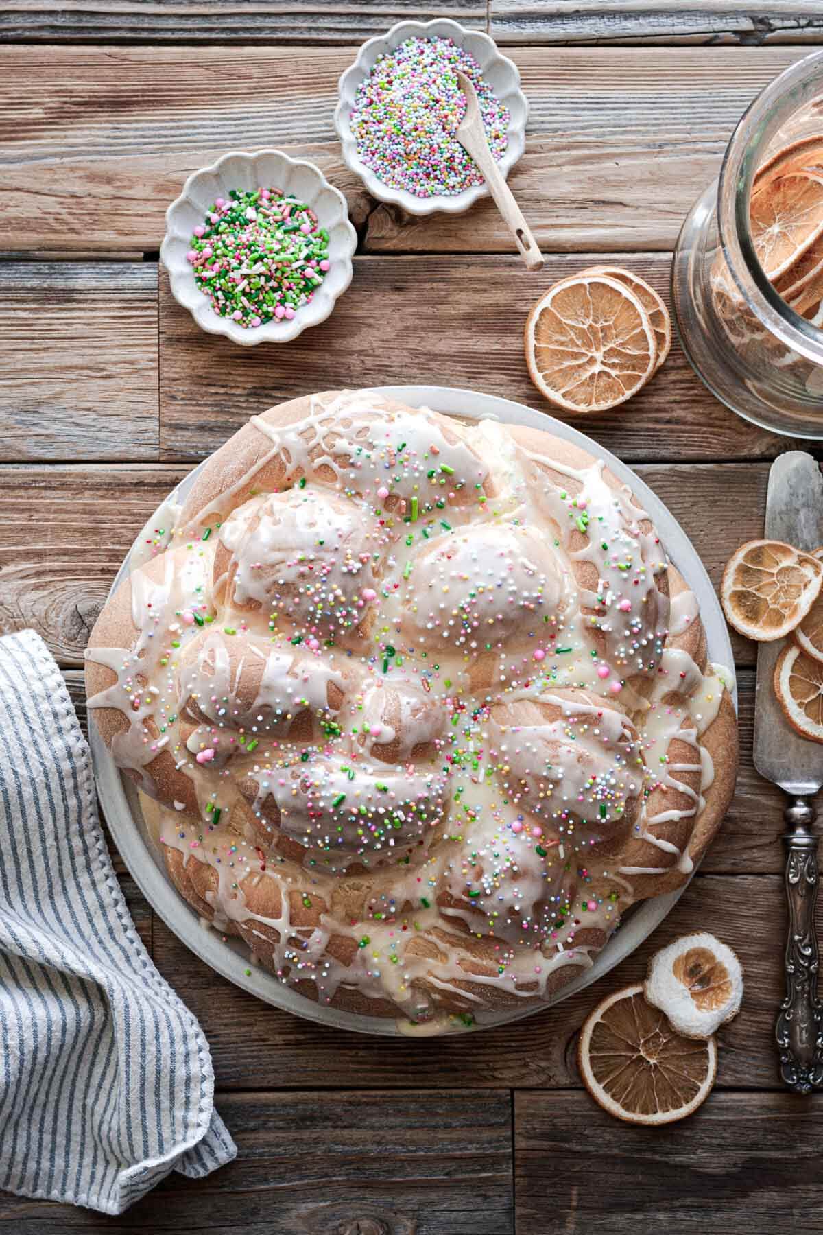 Braided loaf of orange cardamom Easter bread with icing and sprinkles.