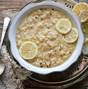 Bowl of lentil soup with sliced lemons.