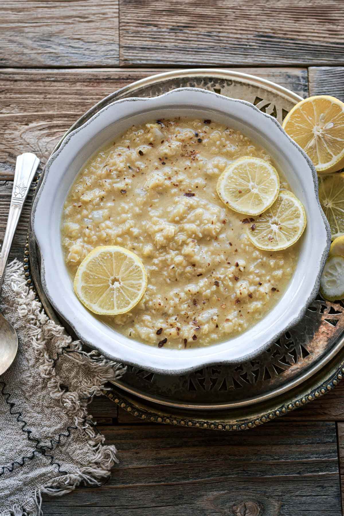 Bowl of lentil soup with sliced lemons.