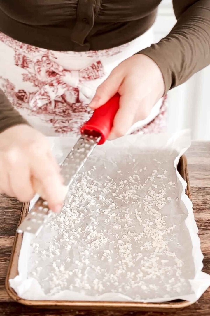 Grating parmesan cheese onto parchment paper.