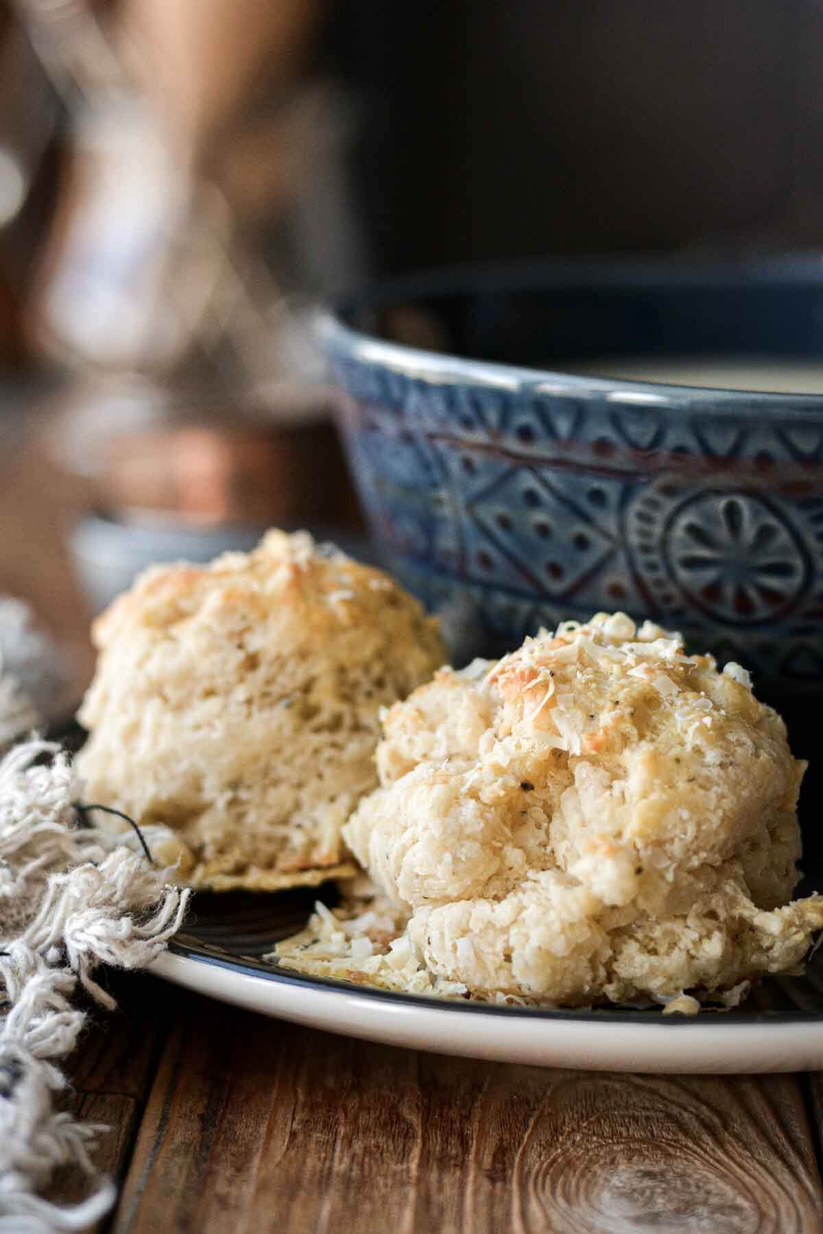 Parmesan pepper drop biscuits on a plate with a bowl of soup.