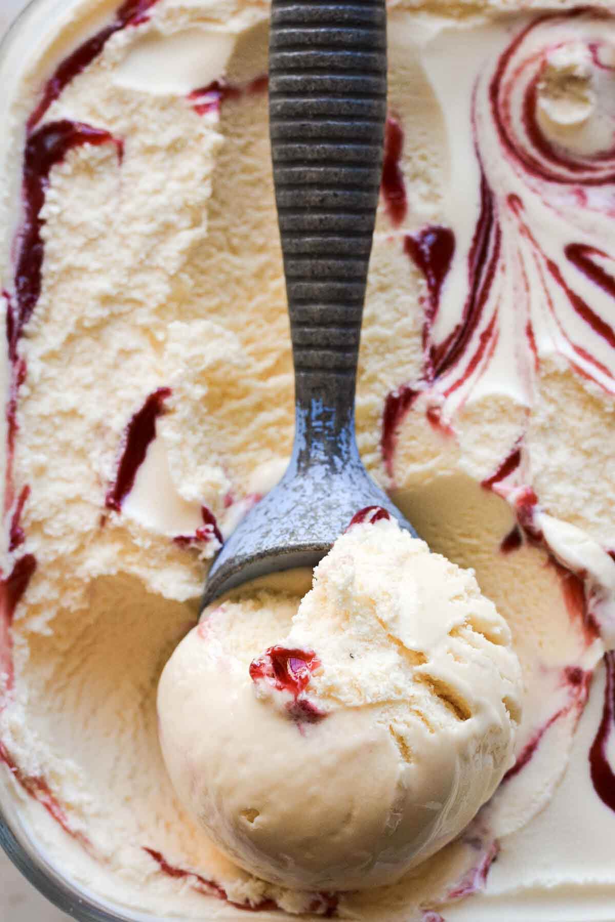 Scoop of lavender lemon raspberry ripple ice cream in a blue vintage ice cream scoop.