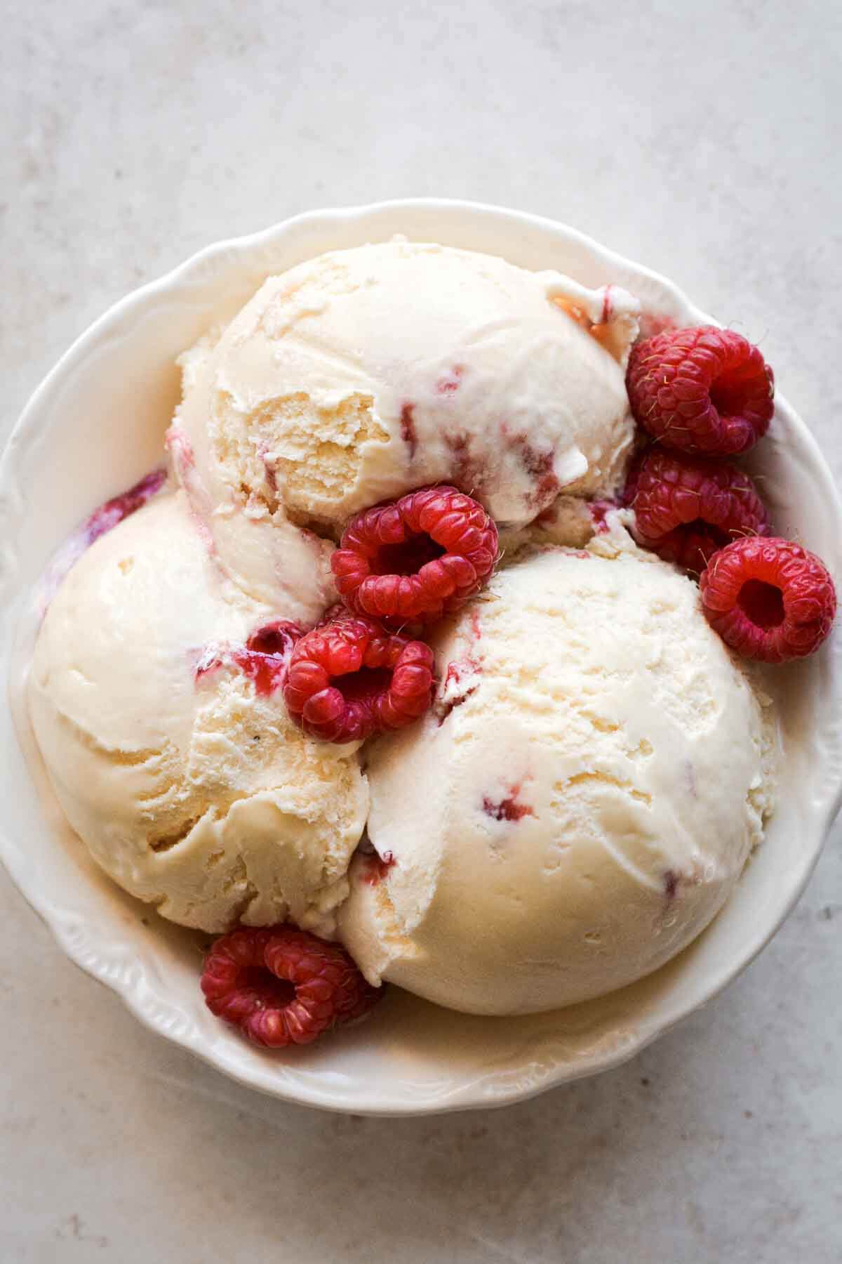 Fresh raspberries on scoops of lemon ice cream.