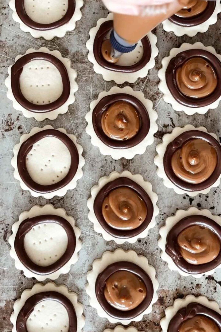 Piping dulce de leche into the centers of shortbread cookies.