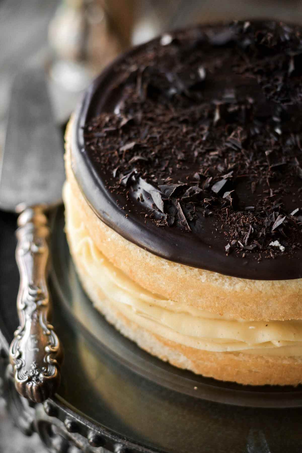 Chocolate ganache and chopped chocolate on top of a Boston cream pie.